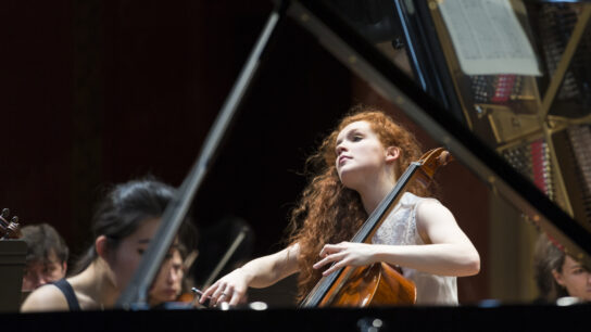 A cellist plays among an orchestra